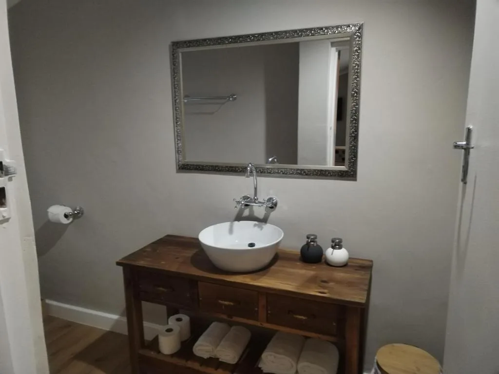Modern bathroom vanity with round white sink and ornate framed mirror