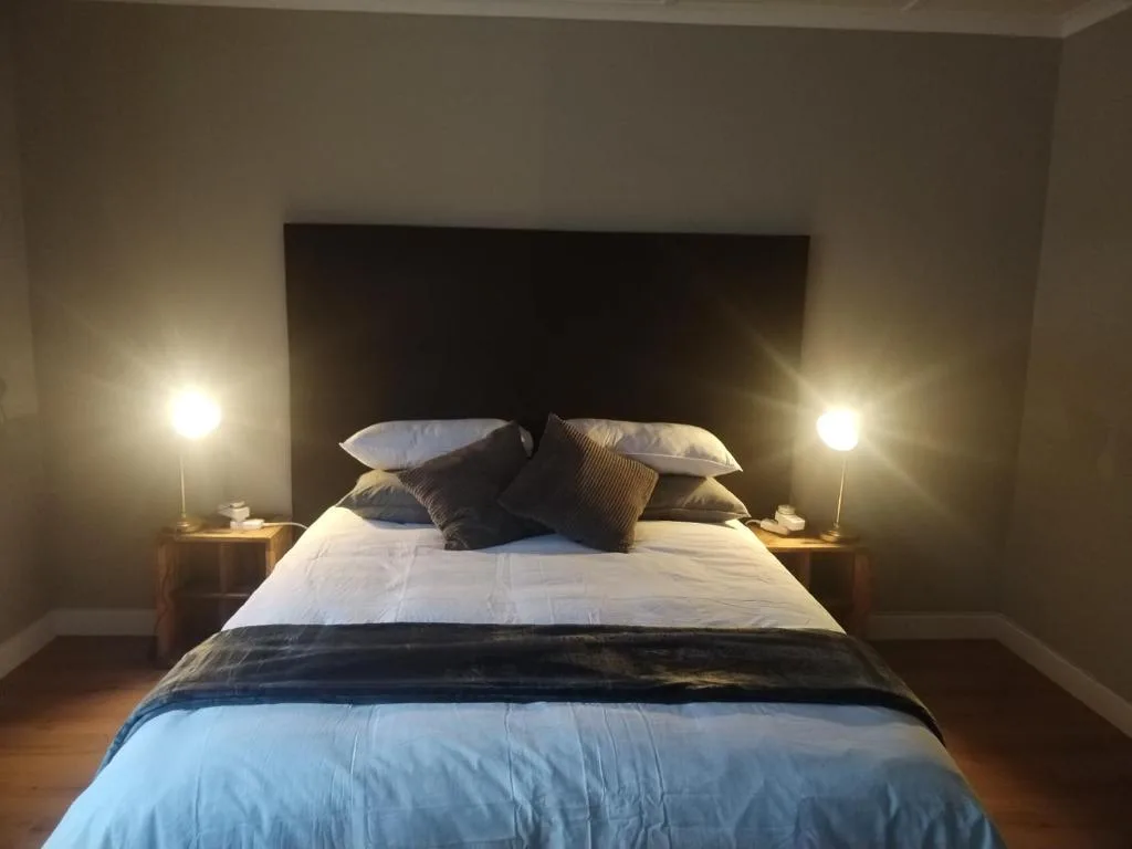 Modern bedroom with queen bed, white linens, blue throw, and bedside lamps