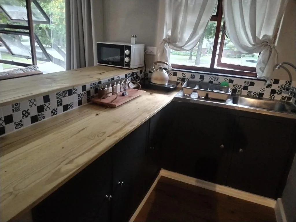 Modern kitchen with wooden countertops, patterned backsplash, sink and microwave