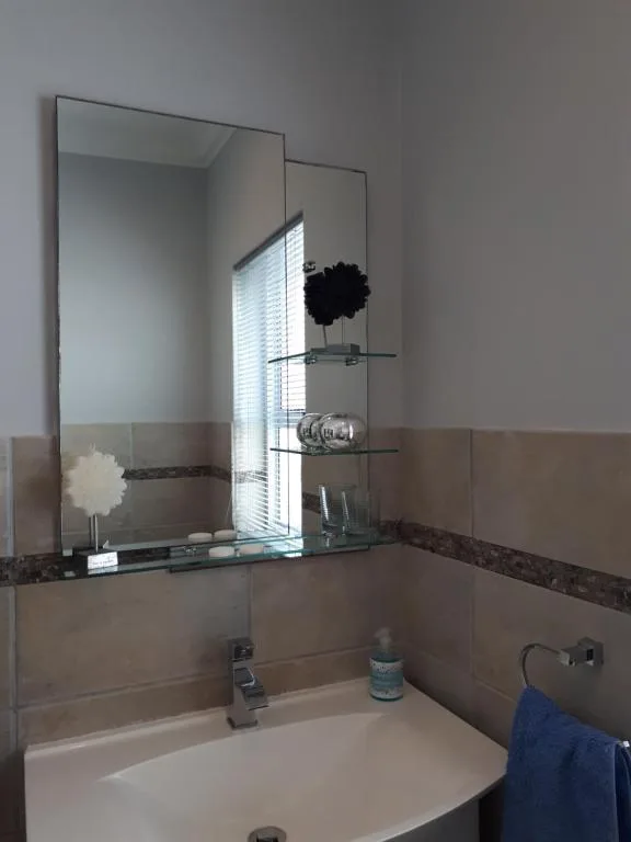 Modern bathroom vanity with large mirror and glass shelving unit