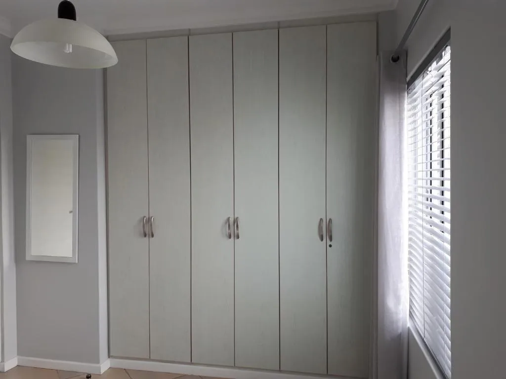 Modern bedroom with floor-to-ceiling built-in white wardrobe and pendant light