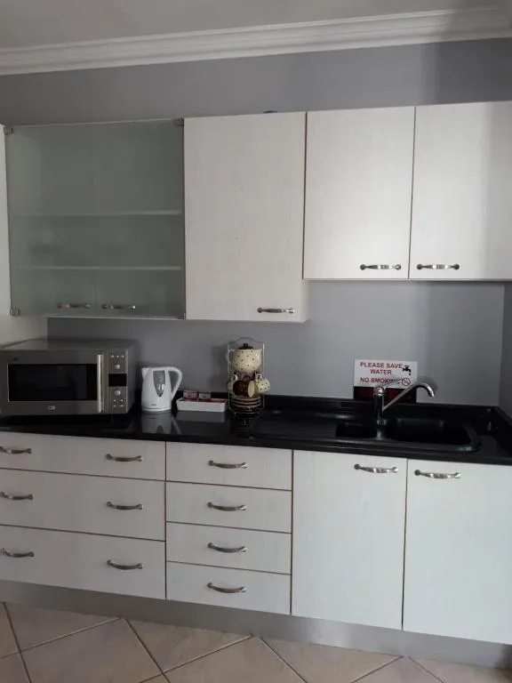 Modern white kitchen with black countertops, microwave, and appliances