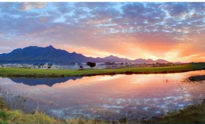 Sunrise over mountains and wetlands with distant houses reflected in water