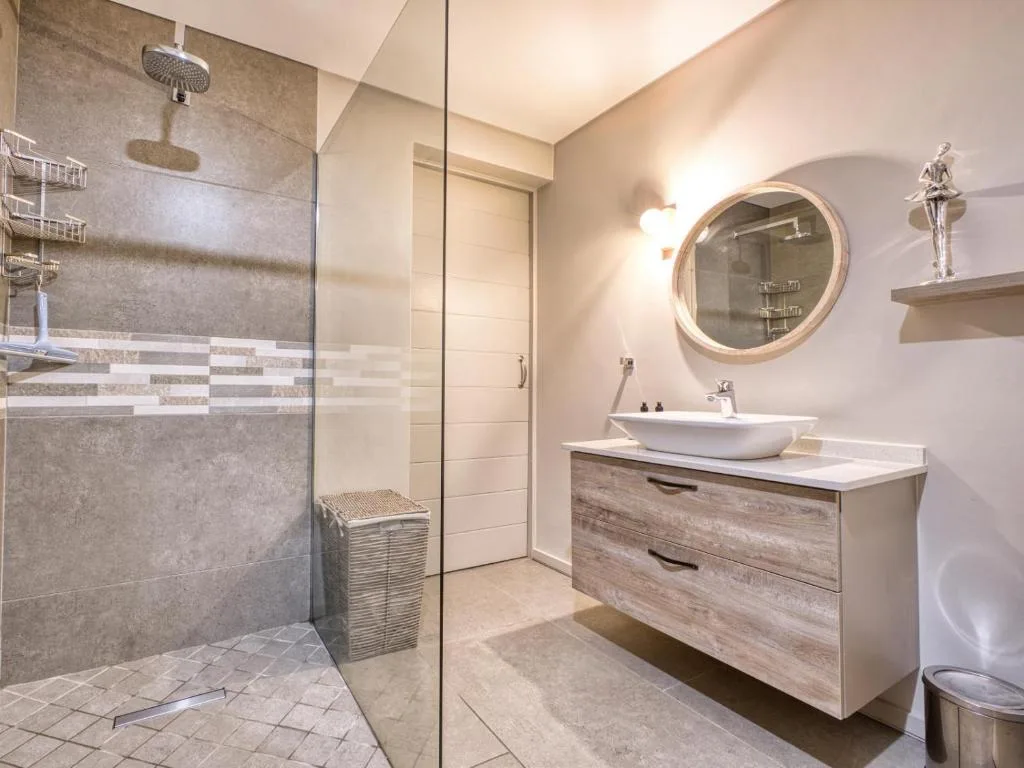Modern bathroom with walk-in shower, vanity sink, and round mirror
