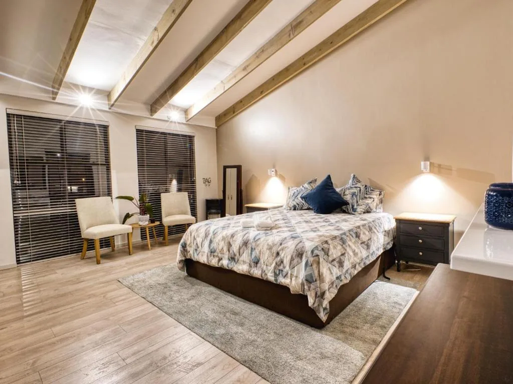 Spacious bedroom with queen bed, exposed beams, and modern furnishings
