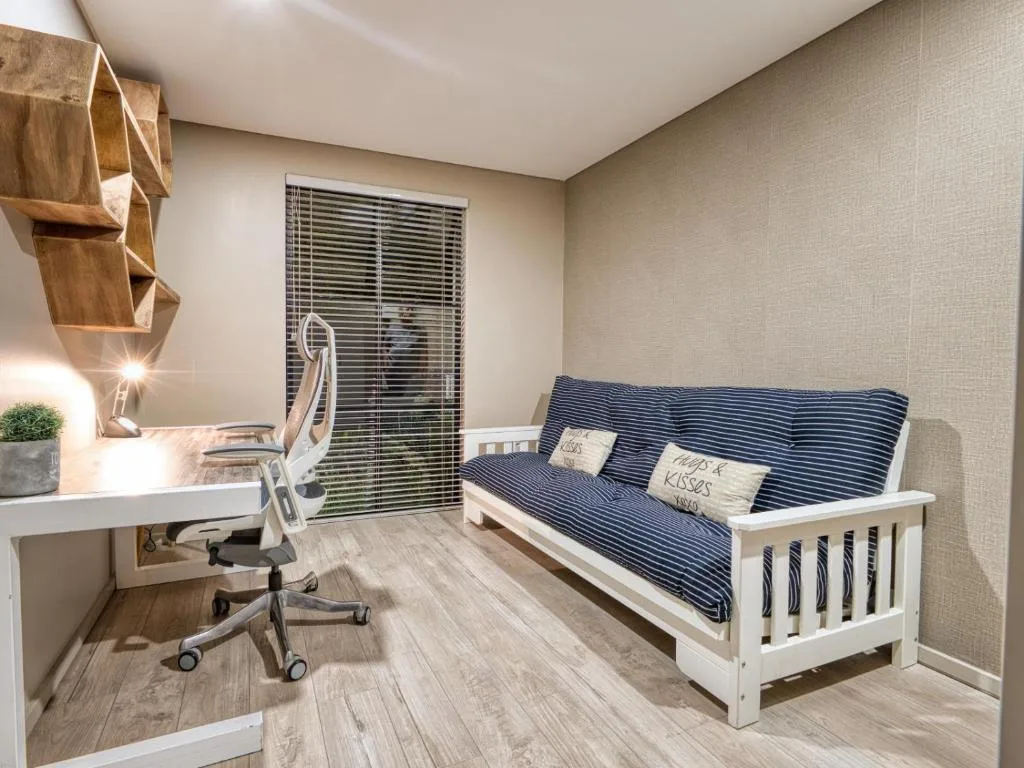 Modern bedroom with white futon, desk workspace, and natural light from window