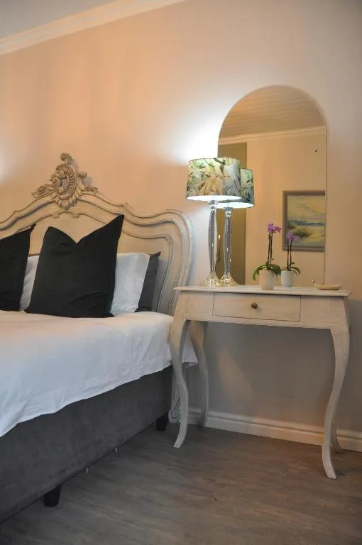 Elegant bedroom with ornate bed frame, black pillows, and vanity mirror