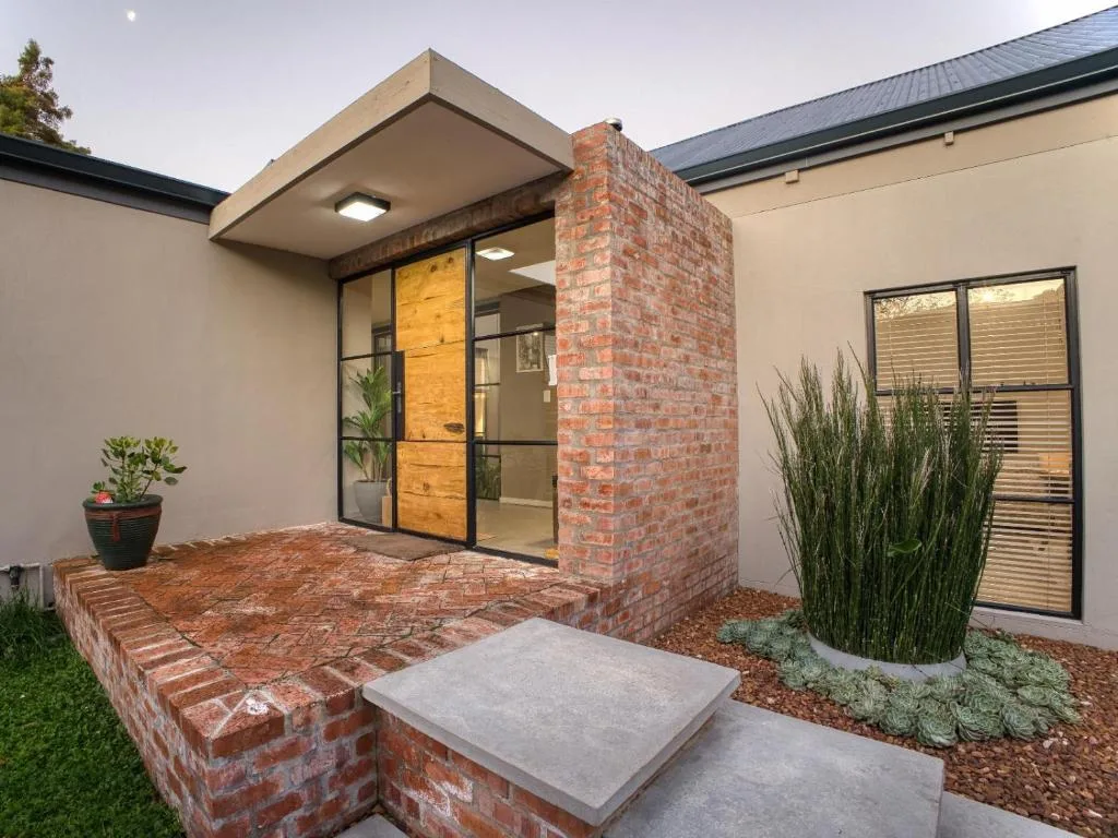 Modern brick entrance with wooden door and contemporary overhang design