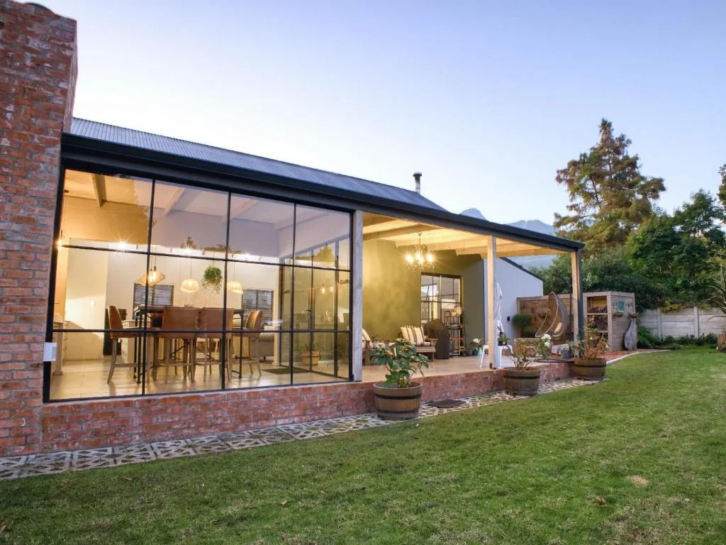 Modern brick home with glass doors and covered deck overlooking manicured lawn
