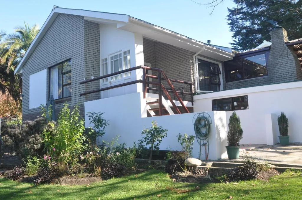 Modern brick and white-rendered home with metal railing entrance stairs and garden landscaping
