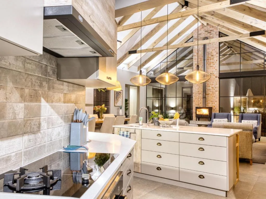 Modern open-plan kitchen with white cabinetry, gas cooktop, and brick walls