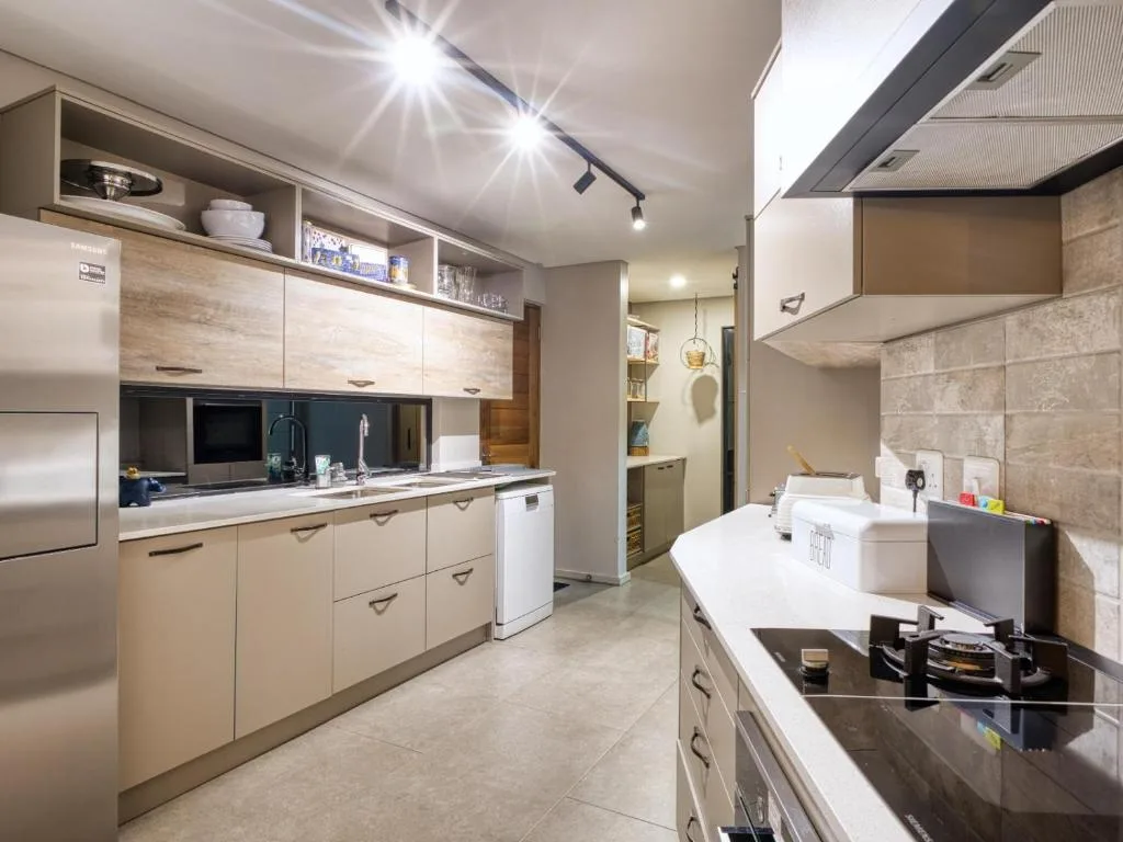 Modern kitchen with light wood cabinetry, stainless steel appliances, and black countertops