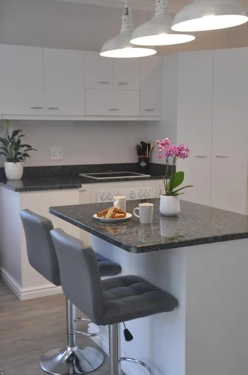 Modern white kitchen with dark granite counters and island seating