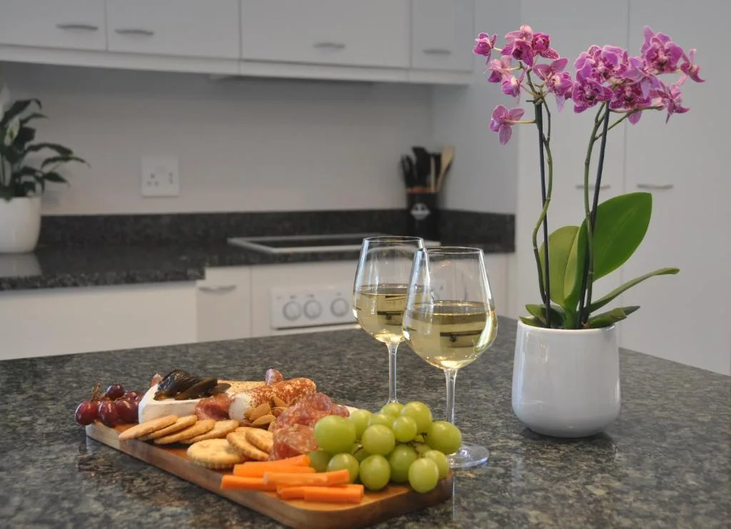 Modern kitchen with granite countertop, wine glasses, charcuterie board, and pink orchid flowers