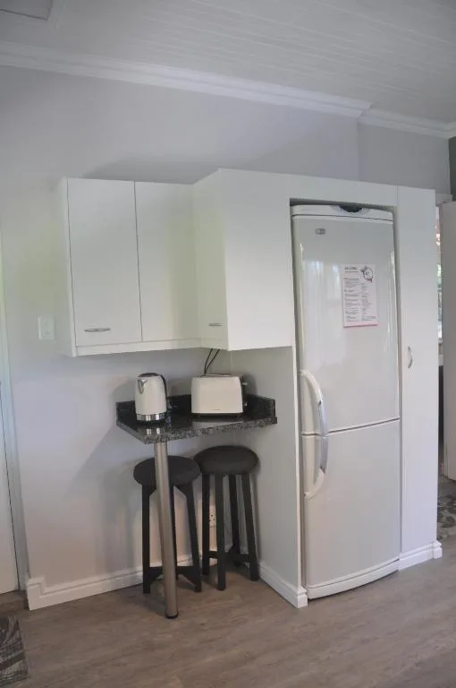 Modern white kitchen with refrigerator, cabinetry, and black bar seating