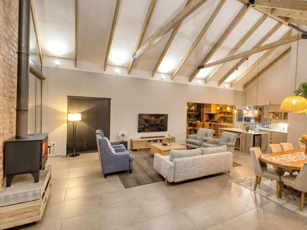 Spacious open-plan lounge with sofas, wood beams, and fireplace