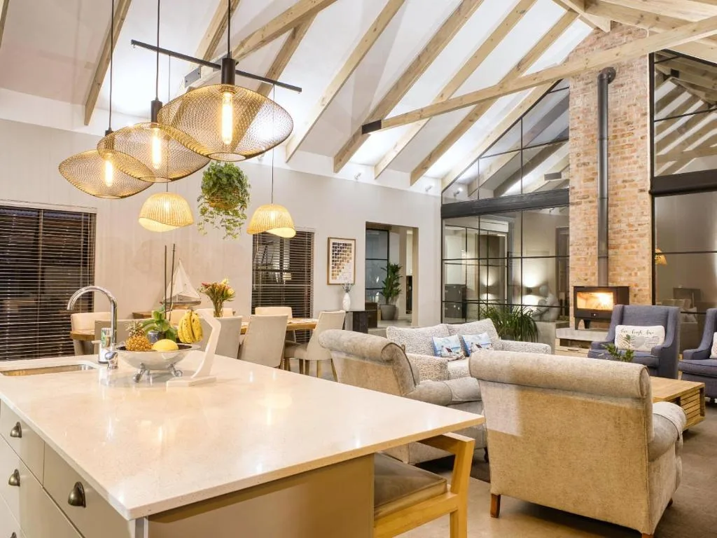 Open-plan living space with sofas, pendant lighting, and brick fireplace