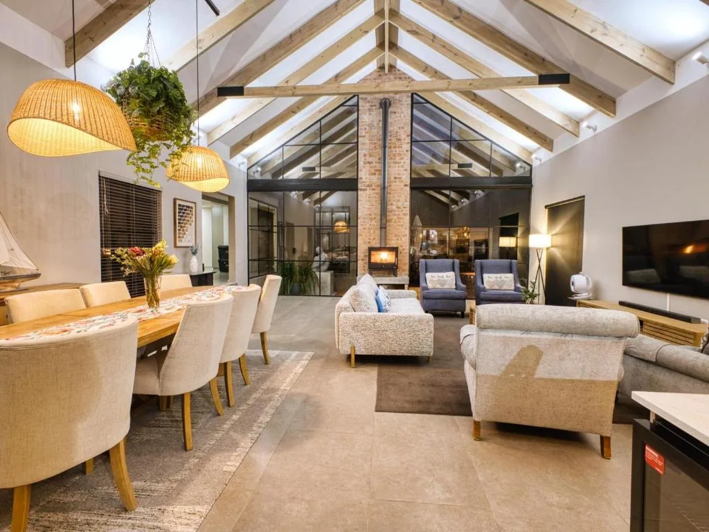 Open-plan lounge with cream sofas, exposed beam ceiling, and fireplace