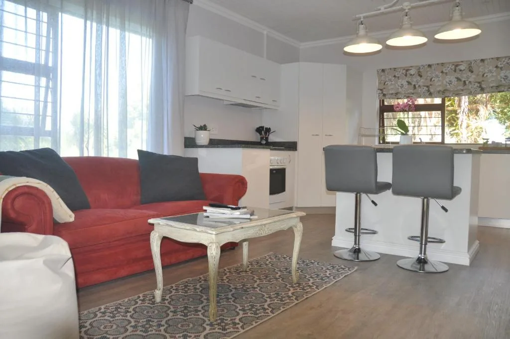 Open-plan lounge with red sofa, coffee table, and integrated kitchen area