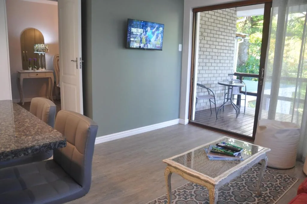 Open-plan lounge with TV, coffee table, and sliding door to deck