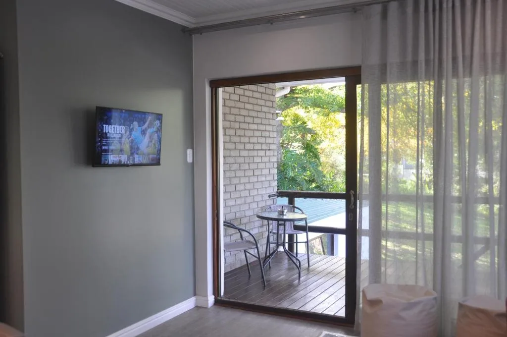 Modern lounge with wall-mounted TV and open sliding doors to deck
