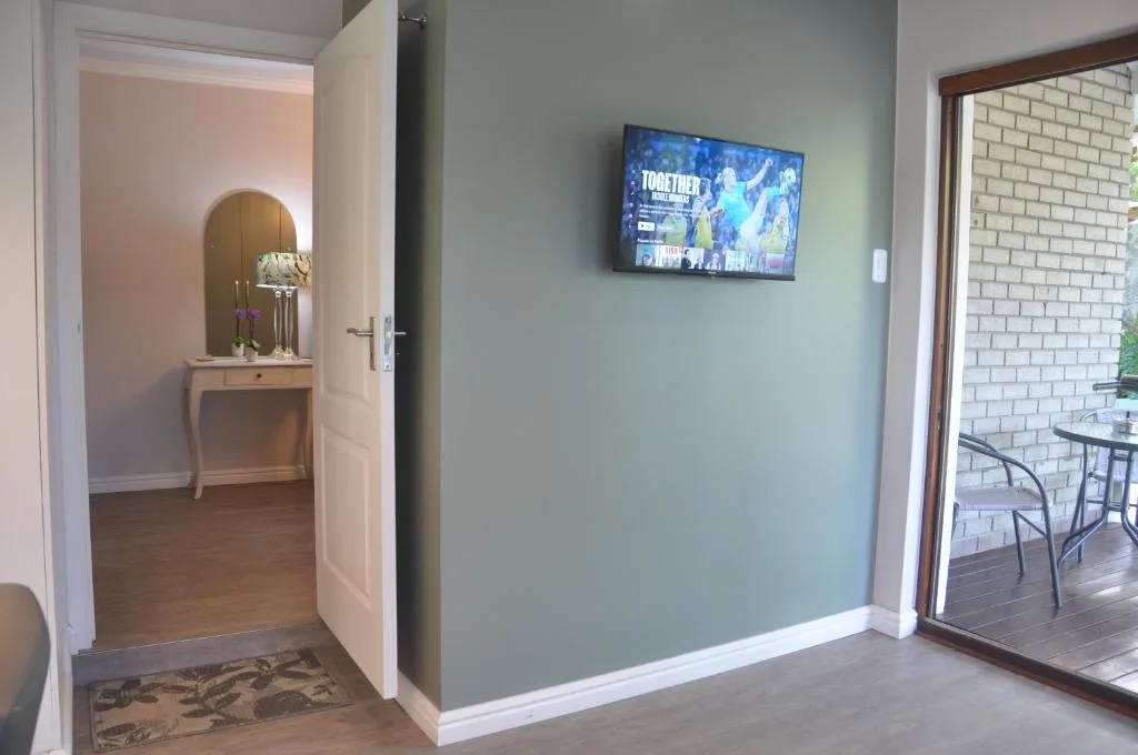 Living room with mounted TV, pale green walls, and open deck access