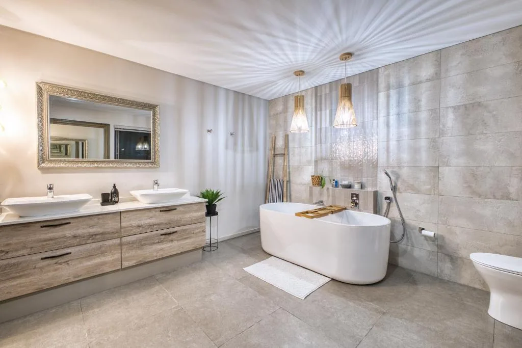 Luxurious bathroom with freestanding tub, dual vanities, and pendant lighting