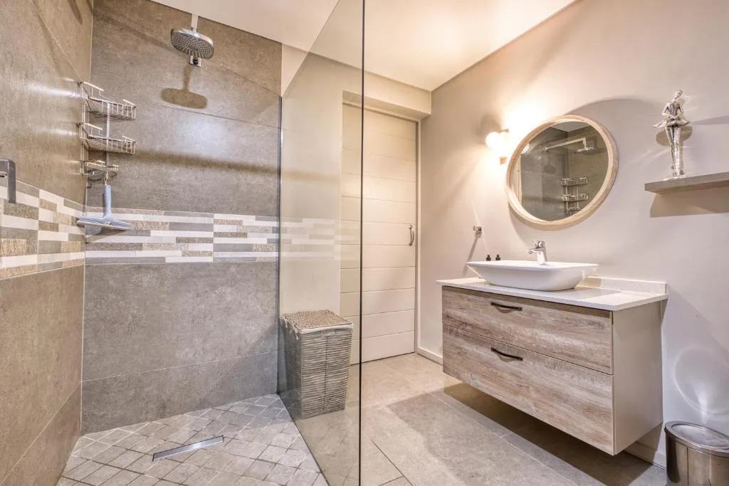 Modern bathroom with walk-in shower, vanity sink, and round mirror