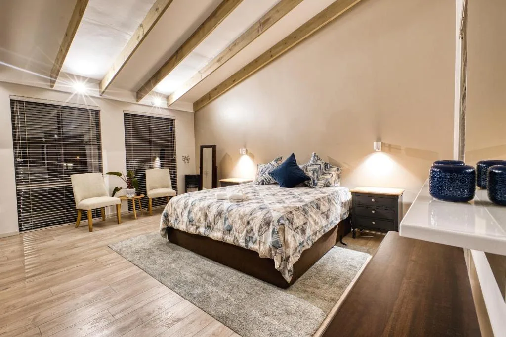 Spacious bedroom with queen bed, exposed beams, and seating area