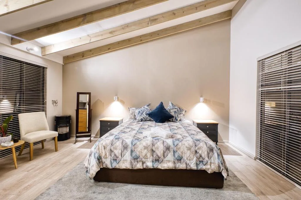 Spacious bedroom with queen bed, exposed wooden beams, and contemporary furnishings