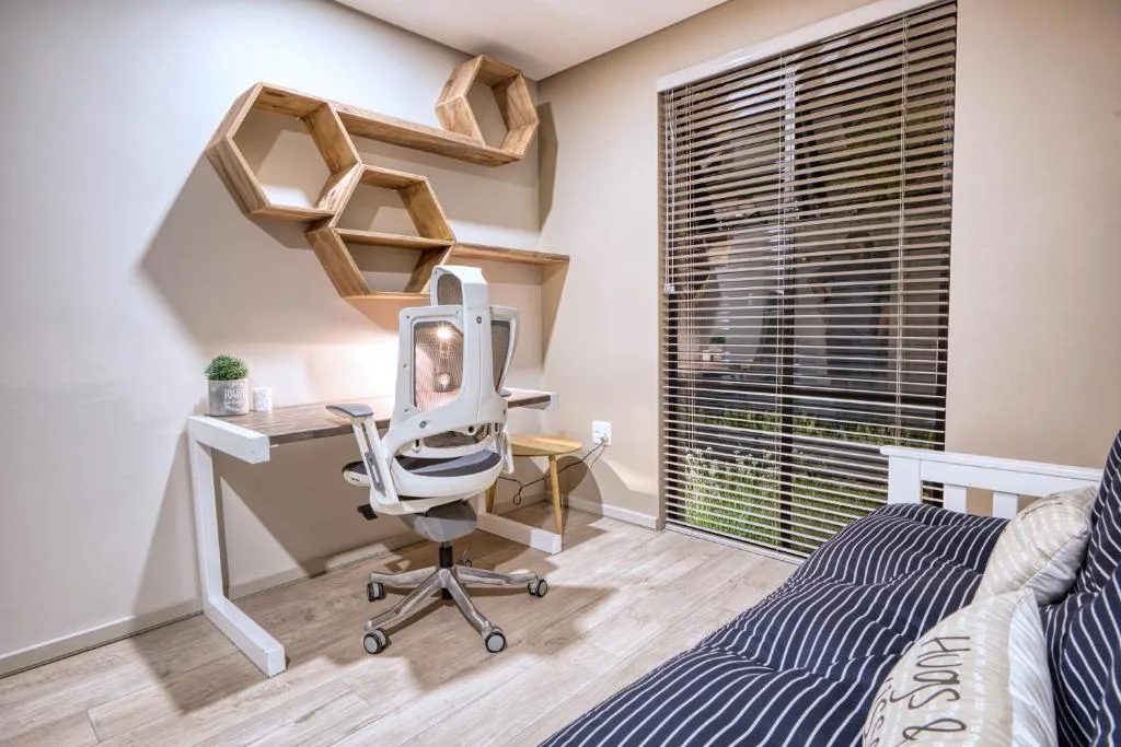 Modern bedroom with work desk, ergonomic chair, and striped bedding