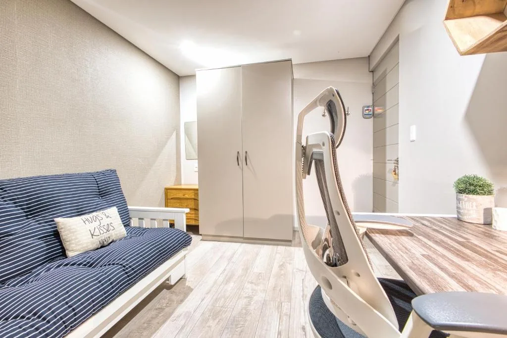 Bright bedroom with blue striped sofa bed and wooden wardrobe closet