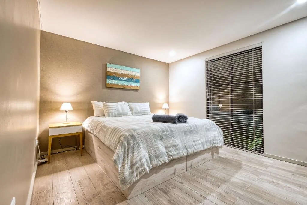 Modern bedroom with queen bed, striped bedding, and wooden flooring throughout