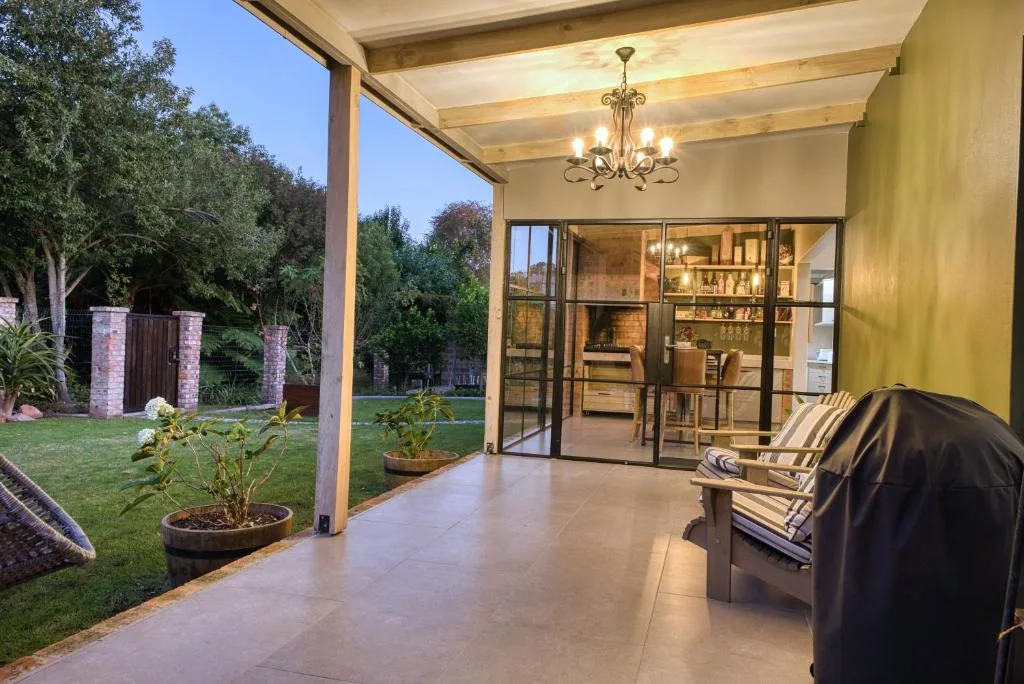 Covered patio with seating overlooking manicured garden and interior spaces