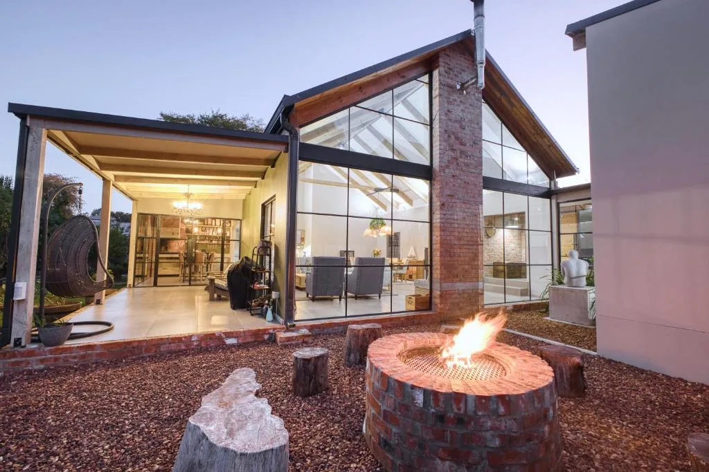 Modern villa exterior with firepit and illuminated glass doors at dusk