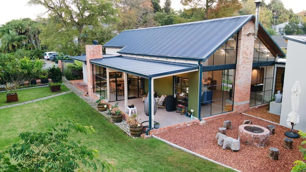 Modern brick villa with blue roof and covered patio area overlooking garden