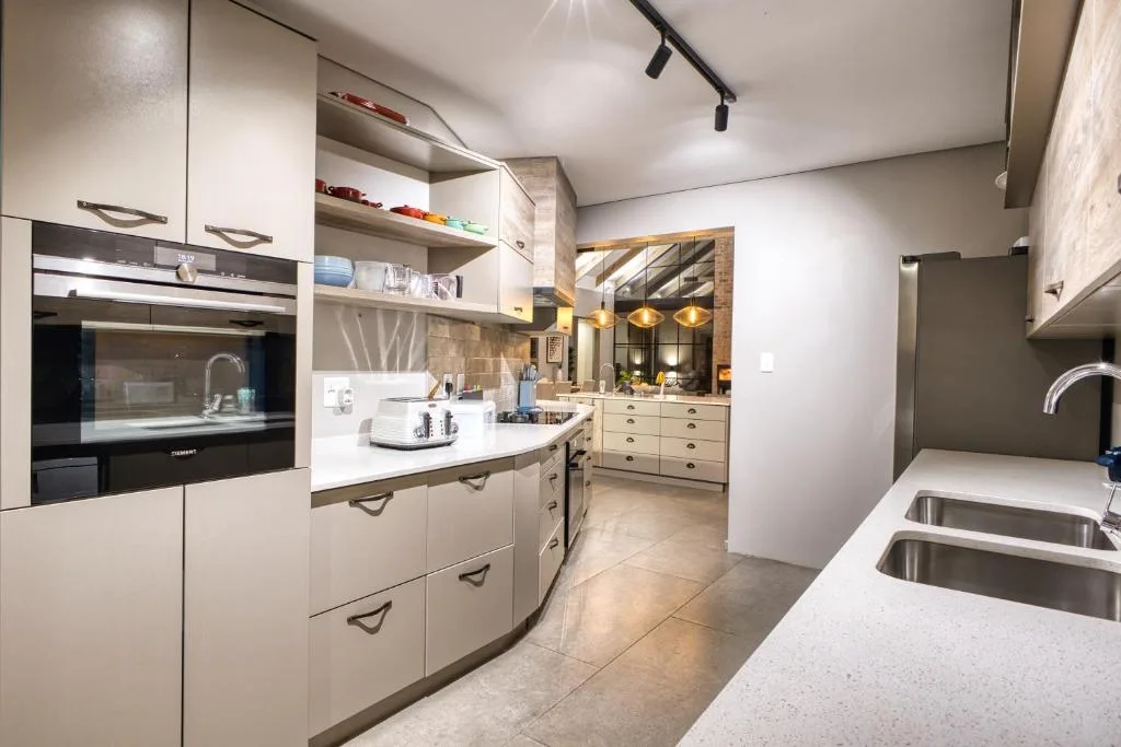 Modern kitchen with white cabinetry, built-in oven, and stainless steel sink