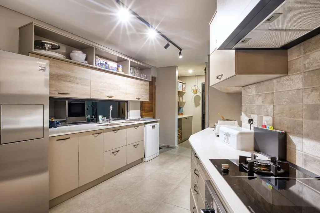 Modern kitchen with light wood cabinetry, stainless steel appliances, and black countertops