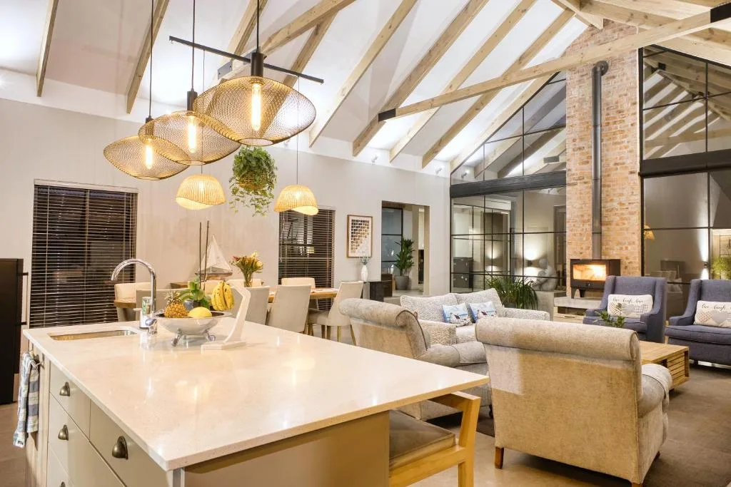 Open-plan lounge with cream sofas, pendant lighting, exposed beams
