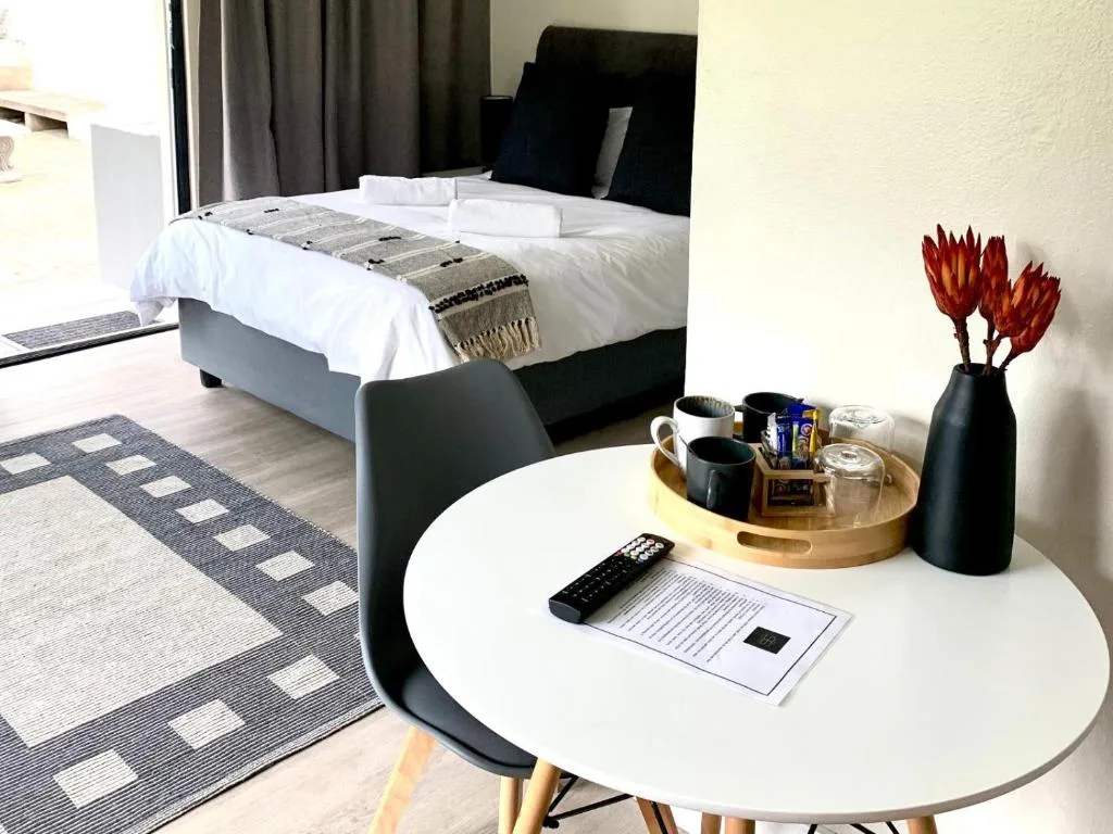 Modern bedroom with white bedding, round side table, and red flowers in vase