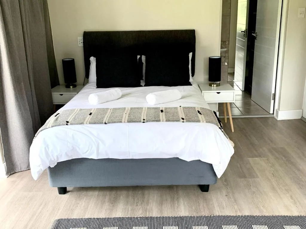 Modern bedroom with black headboard, white bedding, and rolled pillows