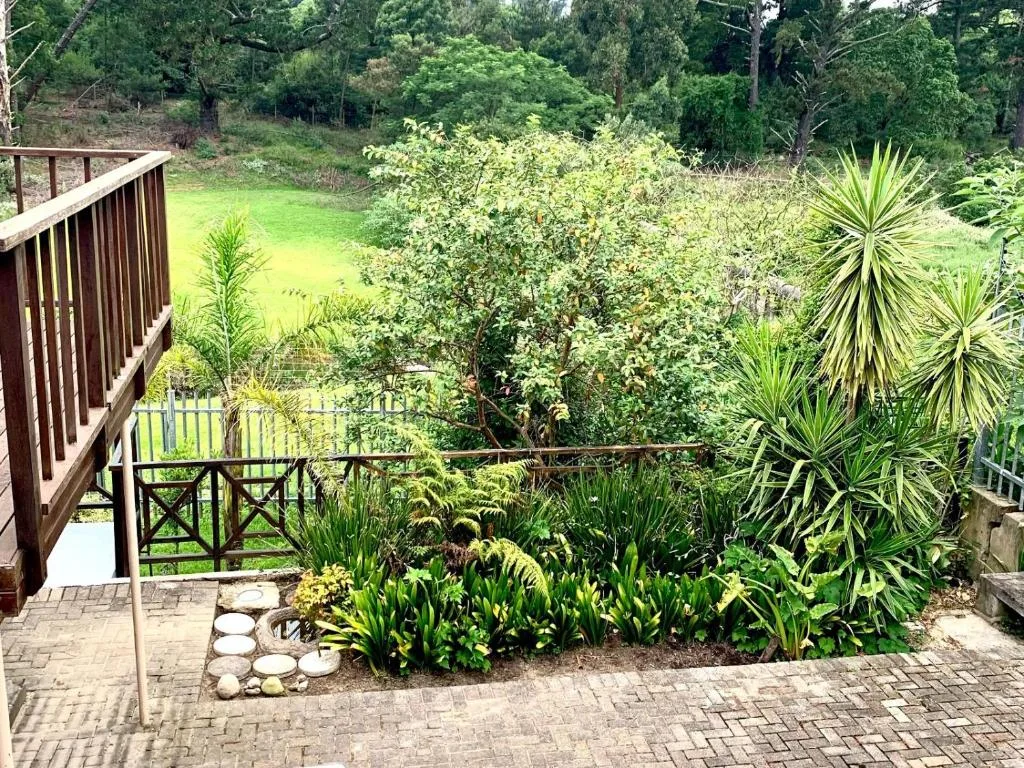 Wooden deck with railings overlooking lush green gardens and natural landscape