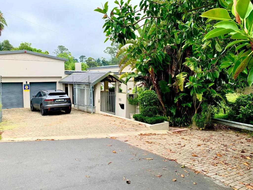 Modern cream and grey holiday home with driveway, garage, and lush tropical gardens