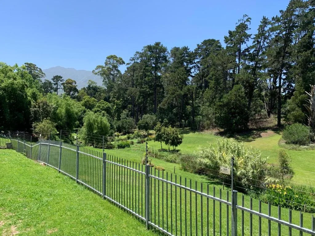 Lush green gardens and mountains visible beyond the property fence