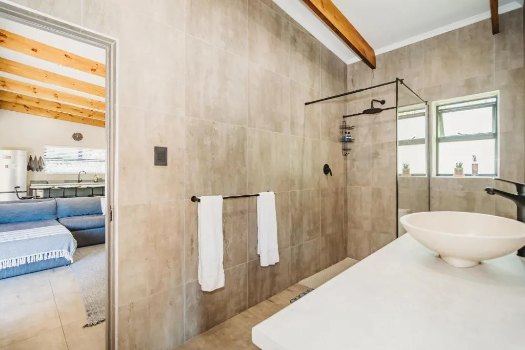 Modern bathroom with large walk-in shower, dual vessel sinks, and wooden beams
