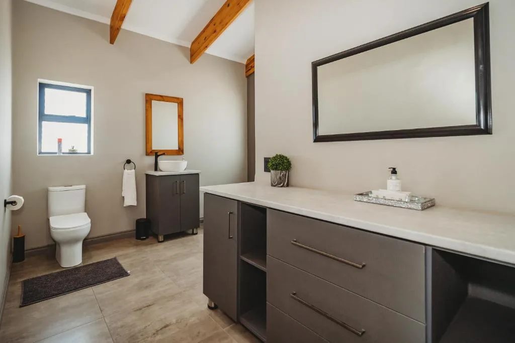 Modern bathroom with dual vanity, toilet, and large mirror