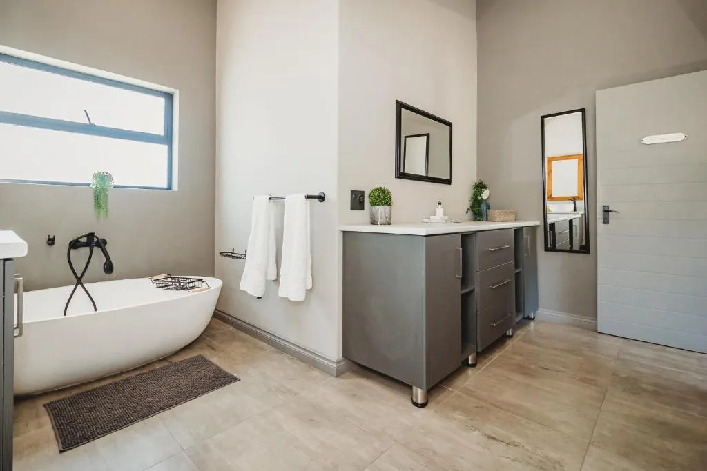 Modern bathroom with freestanding tub, dark vanity, and framed mirrors