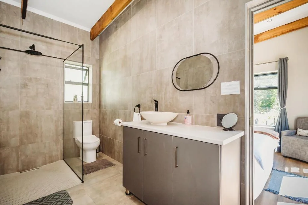 Modern bathroom with walk-in shower, double vanity, and round mirror