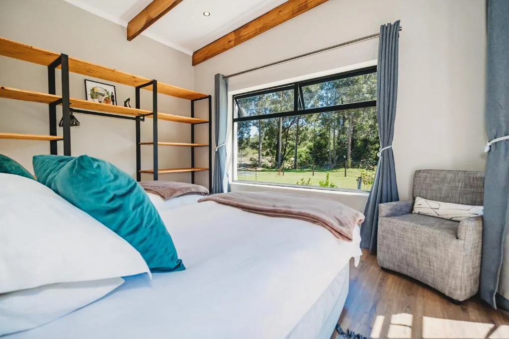 Bright bedroom with queen bed, turquoise pillows, wooden beams, garden views