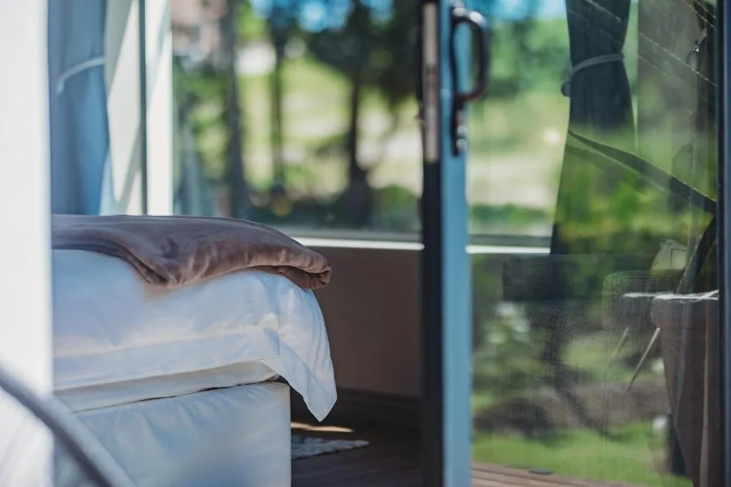 Bed with white linens near open window overlooking garden property